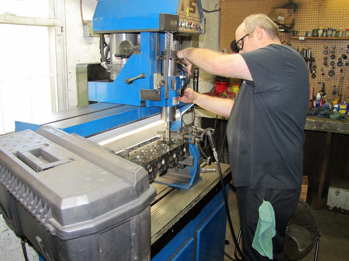 Technician operating boring machine on cylinder head
