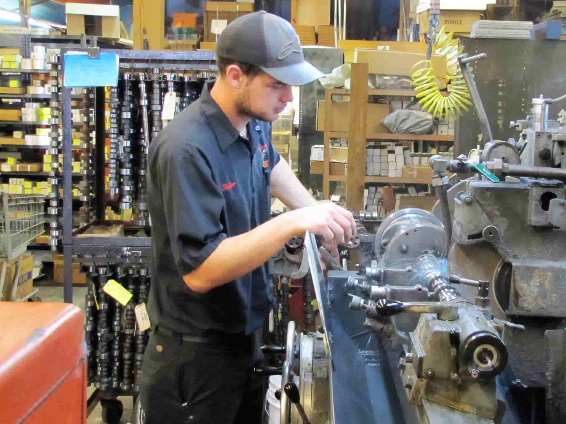 Technician machining engine part in workshop